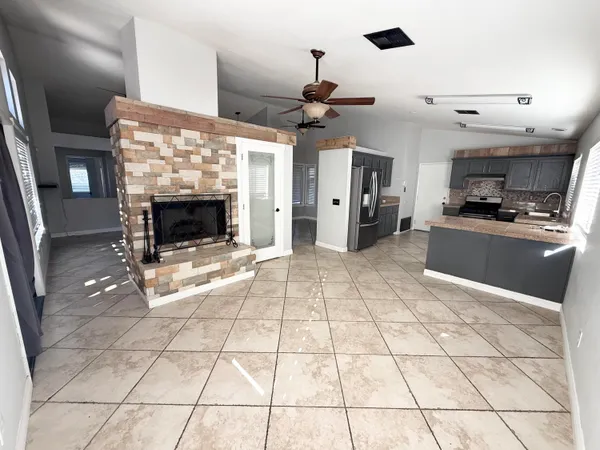 a living room with stainless steel appliances kitchen island granite countertop a rug a stove and a refrigerator