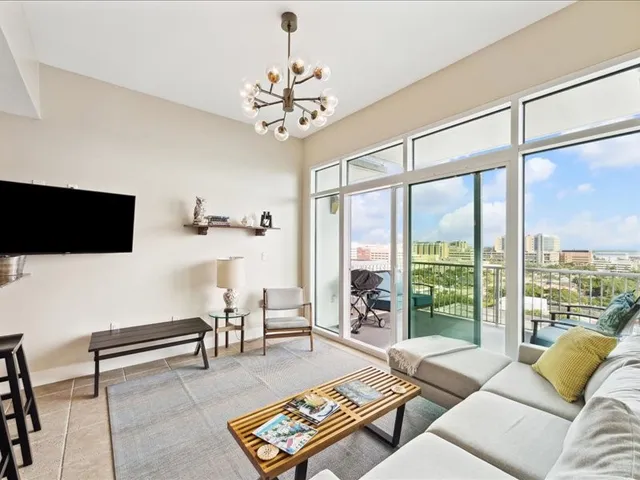 a living room with furniture a flat screen tv and a floor to ceiling window