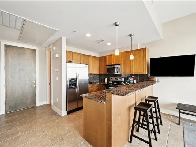 a kitchen with stainless steel appliances kitchen island granite countertop a refrigerator and a stove top oven