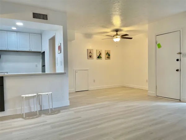 an empty room with wooden floor ceiling fan and windows