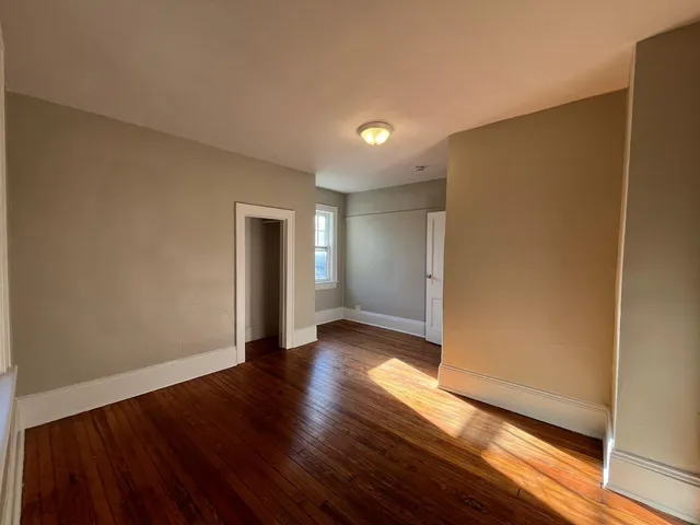 a view of an empty room with wooden floor and closet