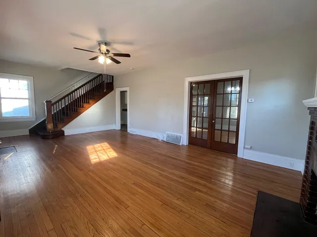 a view of empty room with wooden floor and fan