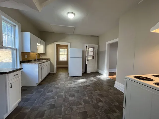 a view of a kitchen with stainless steel appliances granite countertop a refrigerator and a stove top oven