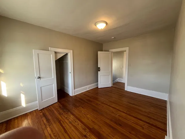 a view of an empty room with window and wooden floor