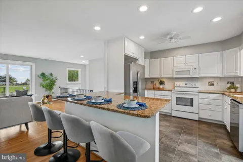 a kitchen with granite countertop white cabinets and white appliances