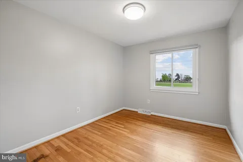 a view of empty room with wooden floor and fireplace