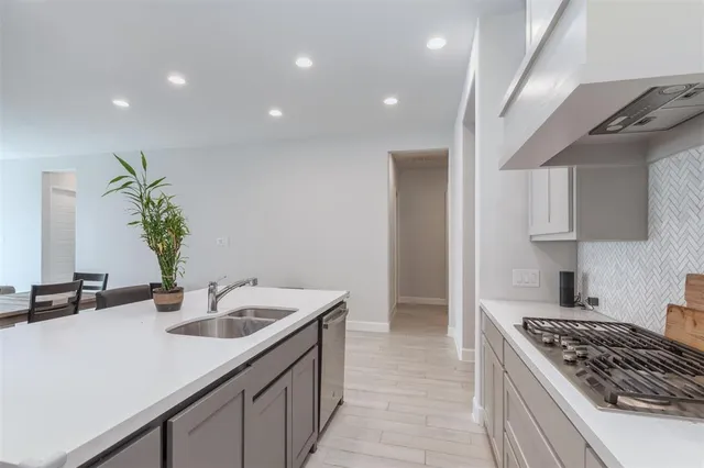 a kitchen with a stove a sink a refrigerator and white cabinets with wooden floor
