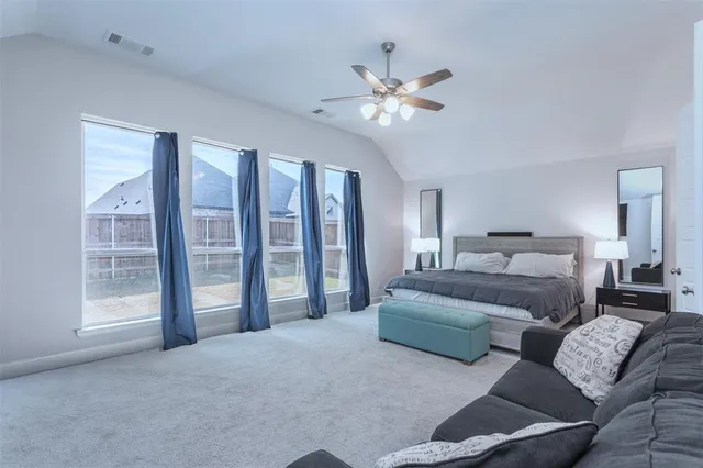 a spacious bedroom with a bed and a flat screen tv