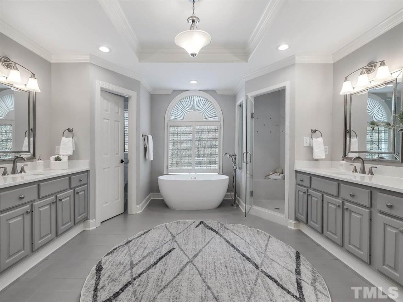 104 Beech Slope Way Cary, NC 27518 - Photo 16 of 30 a spacious bathroom with a double vanity sink a large mirror and a bathtub