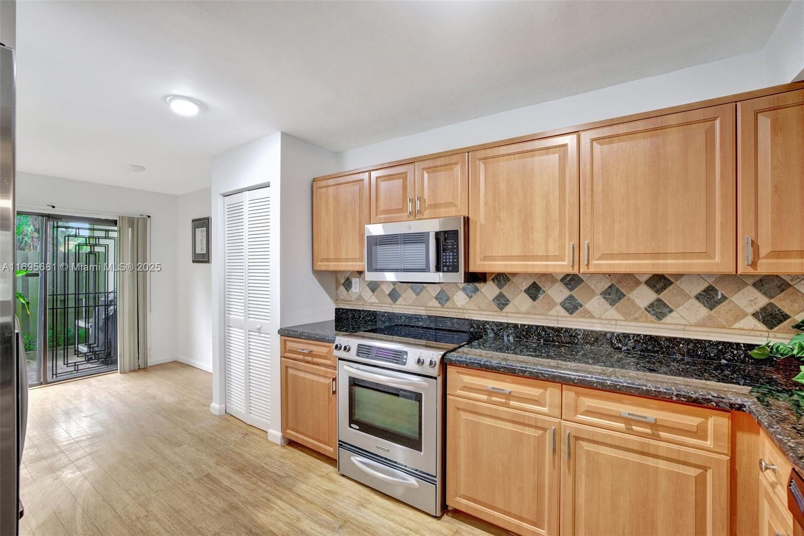 93 Northeast 17th Court, Unit 93 Fort Lauderdale, FL 33305 - Photo 3 of 43 a kitchen with stainless steel appliances granite countertop a stove a sink and white cabinets with wooden floor