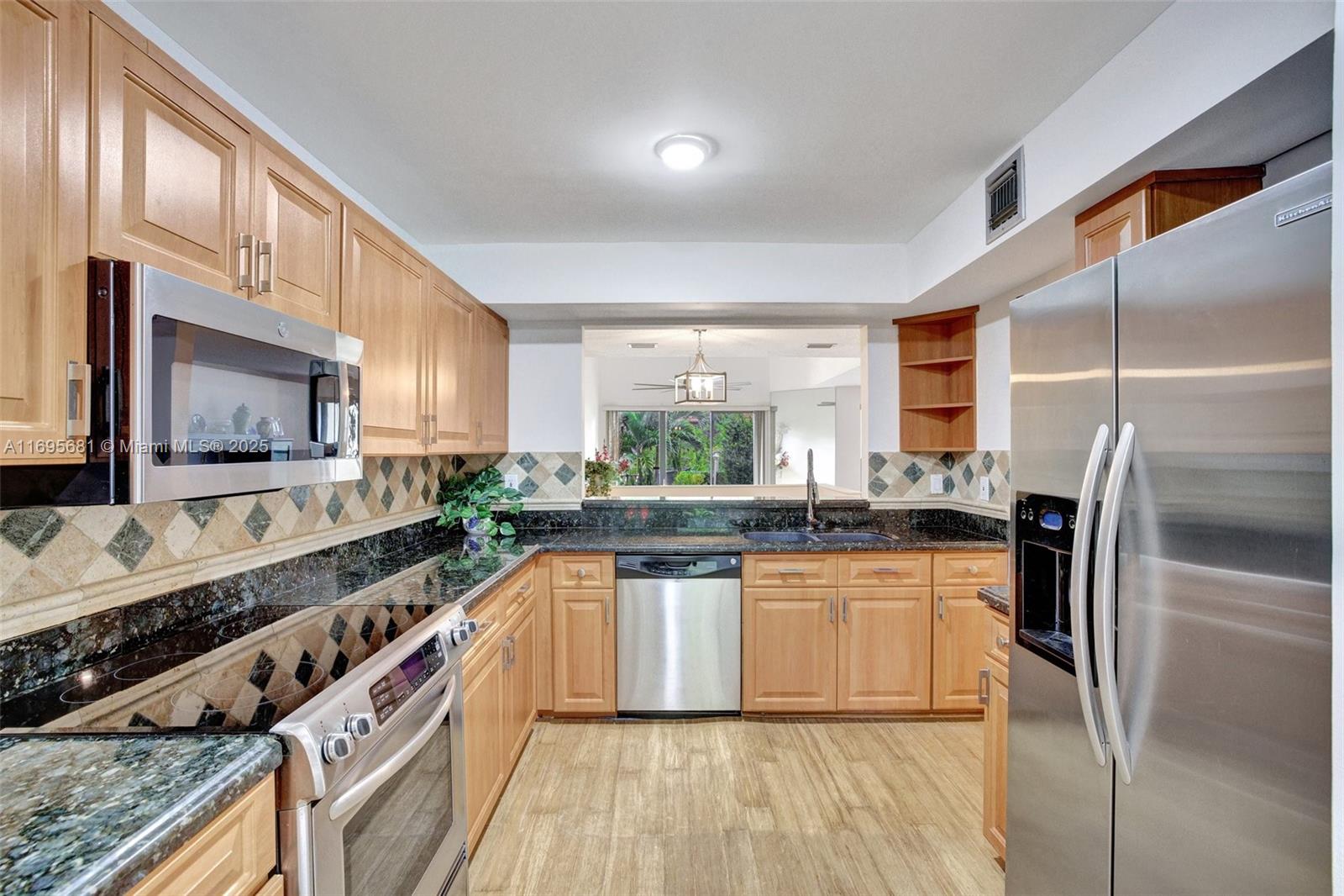 93 Northeast 17th Court, Unit 93 Fort Lauderdale, FL 33305 - Photo 4 of 43 a large kitchen with stainless steel appliances granite countertop a stove a sink and a refrigerator