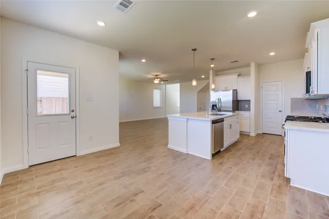 a view of kitchen with kitchen island wooden floor center island and stainless steel appliances