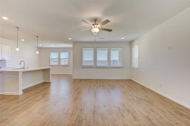 a view of an empty room with window and wooden floor