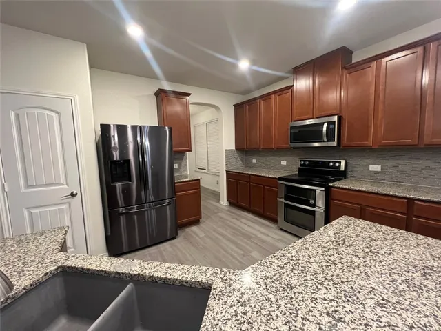 a kitchen with stainless steel appliances granite countertop a refrigerator and a stove top oven