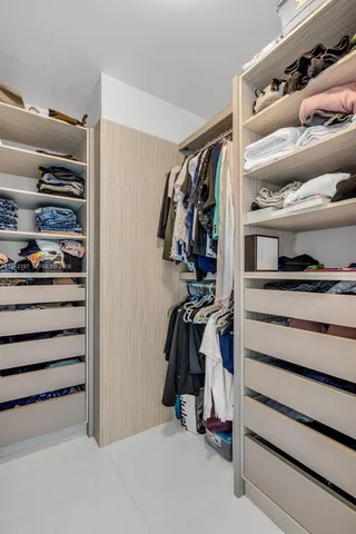 a view of walk in closet with clothes and shoes