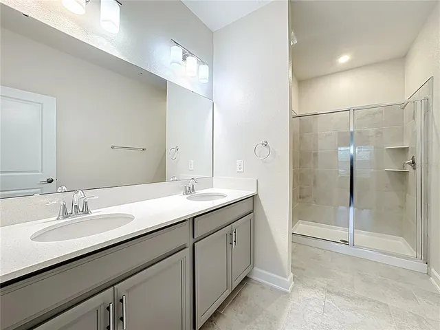 a bathroom with a double vanity sink a mirror and a shower