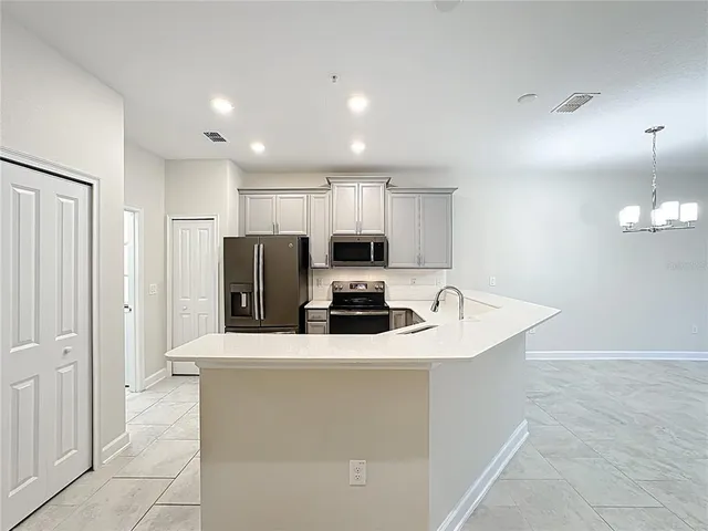 a kitchen with stainless steel appliances granite countertop a sink a microwave a refrigerator and a stove