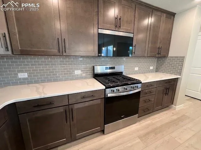 a kitchen with granite countertop stainless steel appliances a sink a stove and cabinets