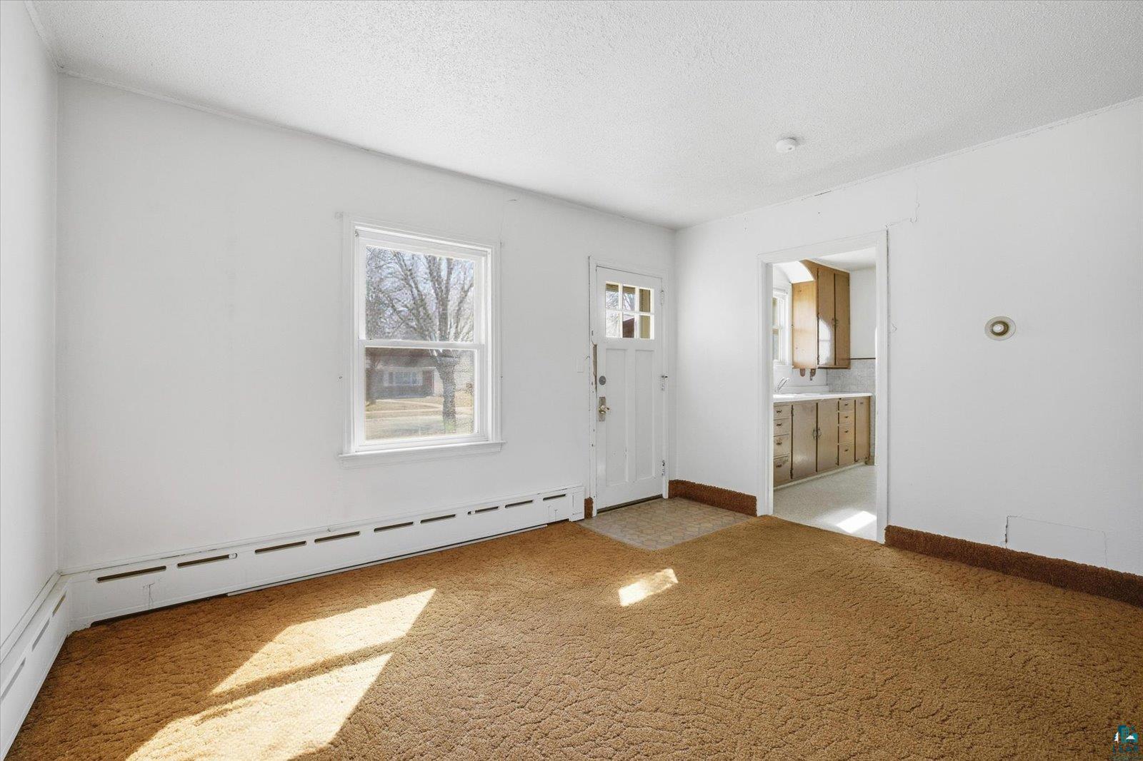 709 Michigan Street Hibbing, MN 55746 - Photo 4 of 47 Foyer entrance with baseboard heating, a textured ceiling, and light colored carpet