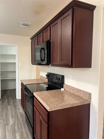 a kitchen with granite countertop a sink a stove and a microwave oven in a cabinets