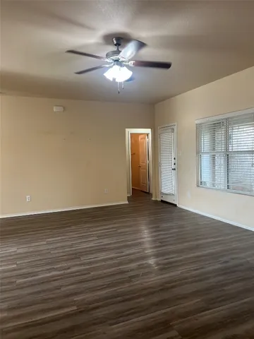 a view of an empty room with wooden floor and chandelier
