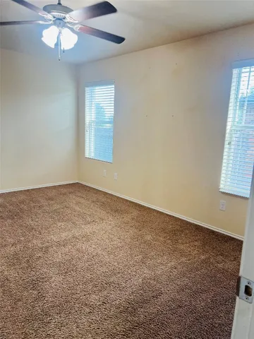 an empty room with windows and fan