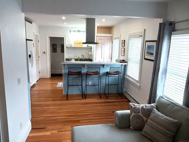 a living room with stainless steel appliances furniture windows and a kitchen view