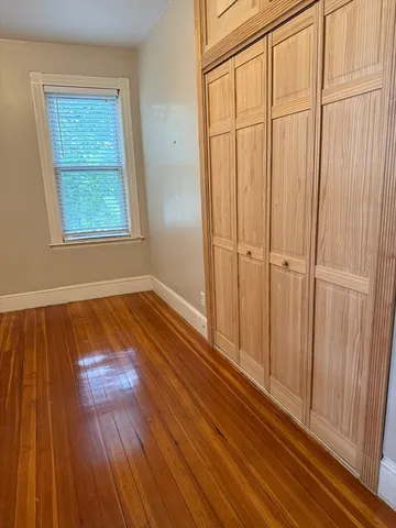 an empty room with wooden floor closet and windows