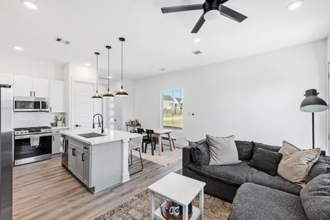 a living room with stainless steel appliances kitchen island furniture and a wooden floor