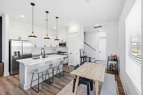 a kitchen with stainless steel appliances kitchen island a table chairs in it and wooden floors