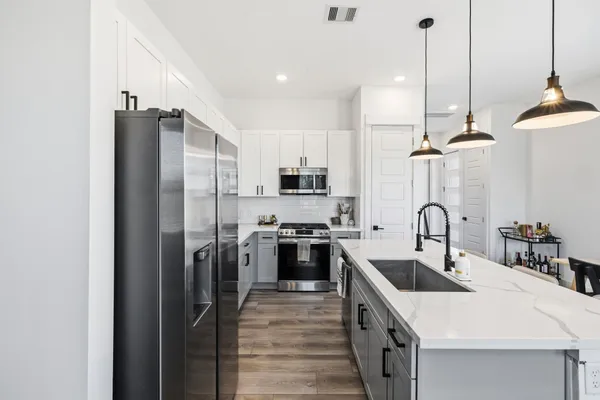 a kitchen with stainless steel appliances a sink a stove a refrigerator and cabinets