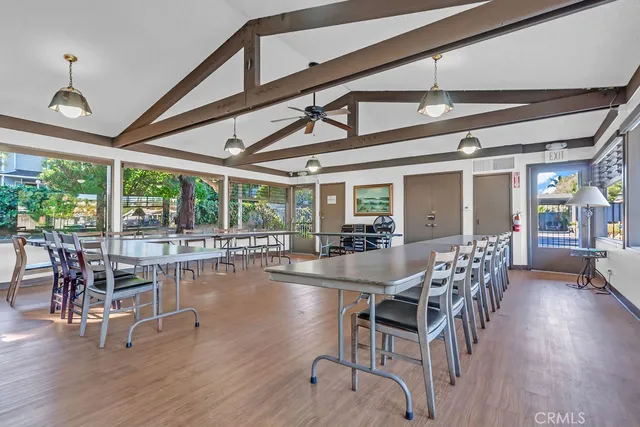 a dining room with wooden floor a chandelier a glass table and chairs