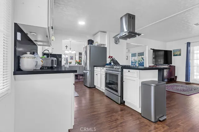 a kitchen with stainless steel appliances granite countertop a refrigerator a stove top oven a sink dishwasher and white cabinets with wooden floor