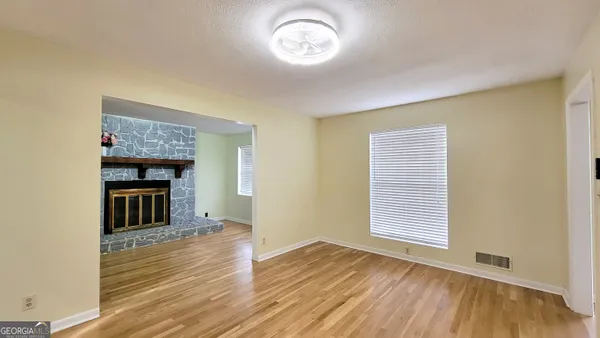 an empty room with wooden floor fireplace and windows