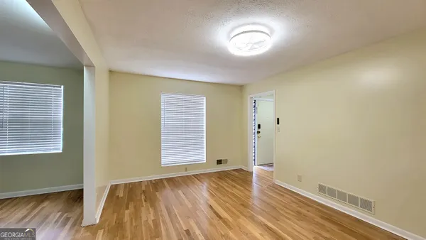 an empty room with wooden floor and windows