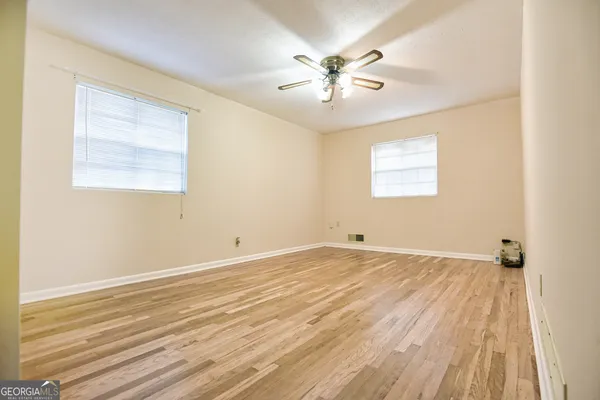 a view of an empty room with wooden floor and a window