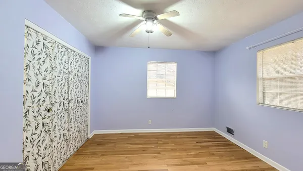 a view of an empty room with window and chandelier fan