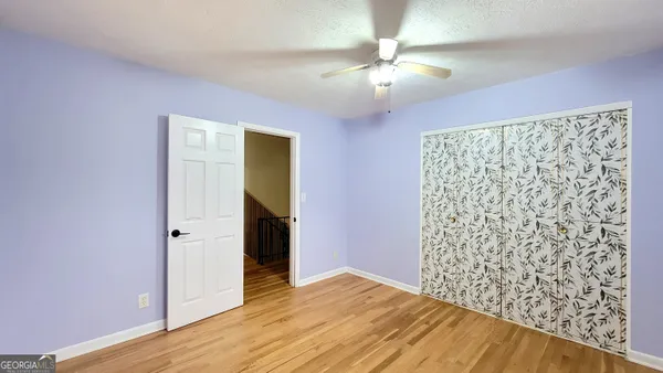 wooden floor in an empty room with a chandelier fan