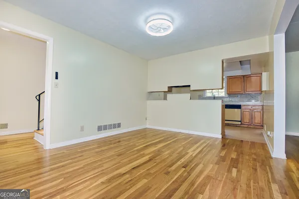 a view of kitchen and empty room with wooden floor