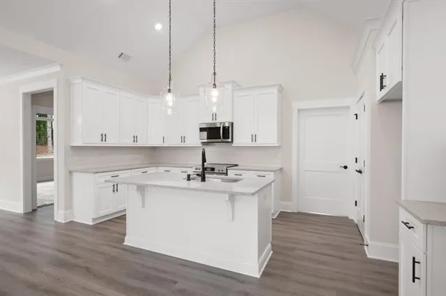 a kitchen with kitchen island a sink a stove a refrigerator and white cabinets with wooden floor