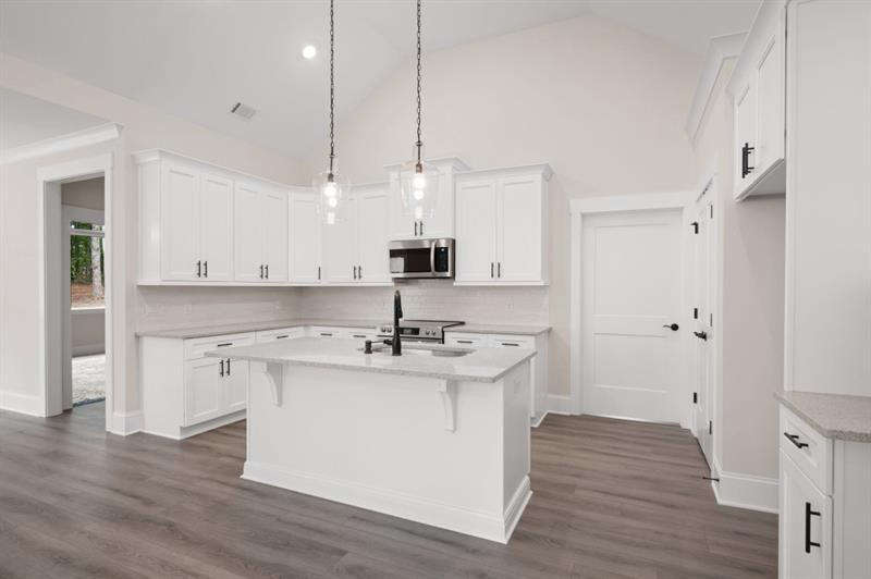 150 Doris Path Temple, GA 30179 - Photo 14 of 36 a kitchen with kitchen island a sink a stove a refrigerator and white cabinets with wooden floor
