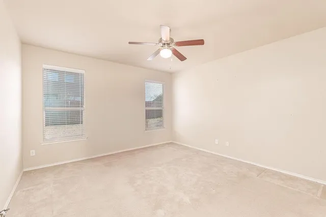 an empty room with windows and fan