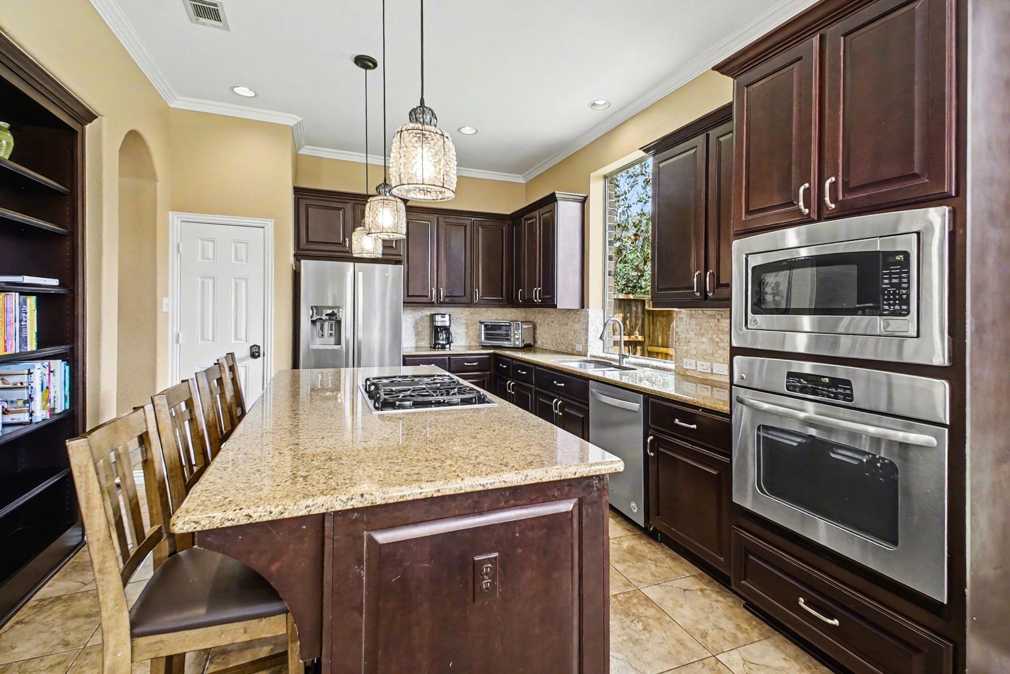 8210 Thunder Ridge Way Missouri City, TX 77459 - Photo 17 of 42 This kitchen features sleek stainless steel appliances, ample cabinetry, and a stylish bookshelf for cookbooks and decor.