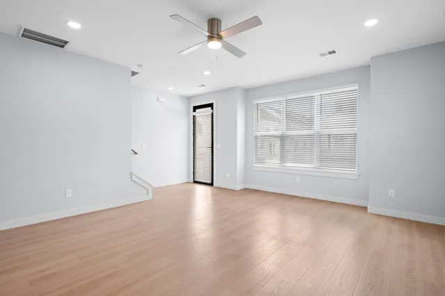 an empty room with wooden floor and windows
