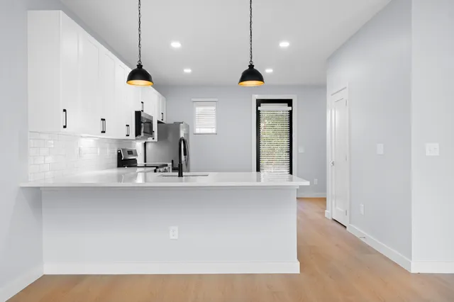 a large kitchen with kitchen island stainless steel appliances a sink a center island and a window