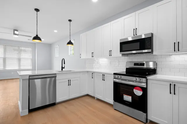 a kitchen with stainless steel appliances granite countertop a sink a stove a microwave and wooden floors