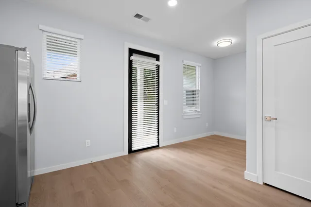 an empty room with wooden floor and windows