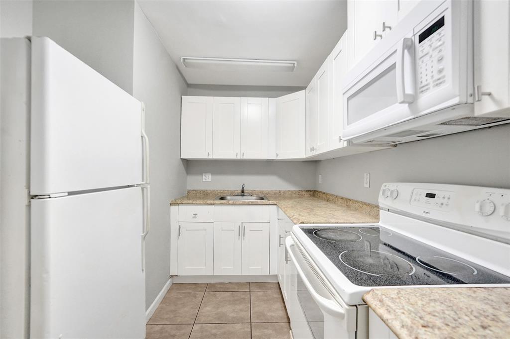 555 Southeast 8th Street, Unit 252 Deerfield Beach, FL 33441 - Photo 14 of 18 a kitchen with a stove a refrigerator and white cabinets