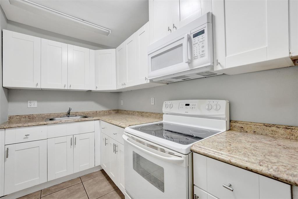 555 Southeast 8th Street, Unit 252 Deerfield Beach, FL 33441 - Photo 15 of 18 a utility room with granite countertop white cabinets and white appliances
