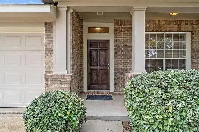 front view of a brick house with a large window and a yard